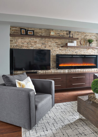 living-room-interior-with-stone-wall-and-fireplace-with-custom-cabinetry-and-gray-leather-chair-on-geometric-rug
