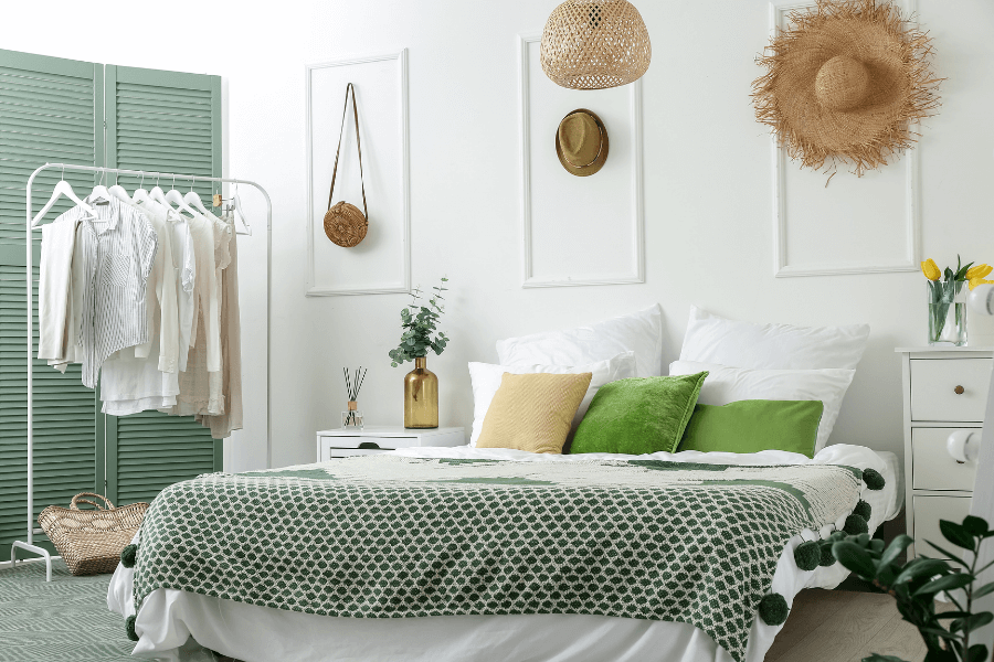 boho design style, hanging hats, green pillows, wicker chandelier, tassel quilt
