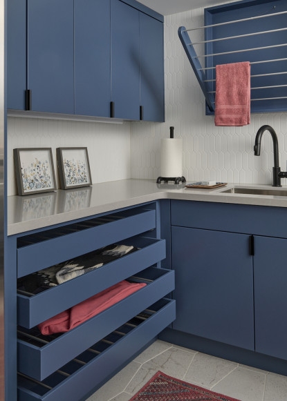 custom-laundry-room-blue-cabinets-pull-out-drying-rack-drawers-quartz-countertops-gray-flooring