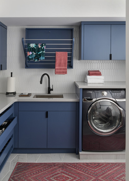 organized-laundry-room-blue-cabinets-pull-down-dry-rack-black-hardware-black-faucet-picket-fence-tile