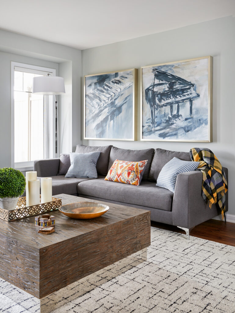Living Room With Gray Sofa And Accent Pillows And Modern Coffee Table And Art Wall With Blue Abstract Painting And Geometric Rug