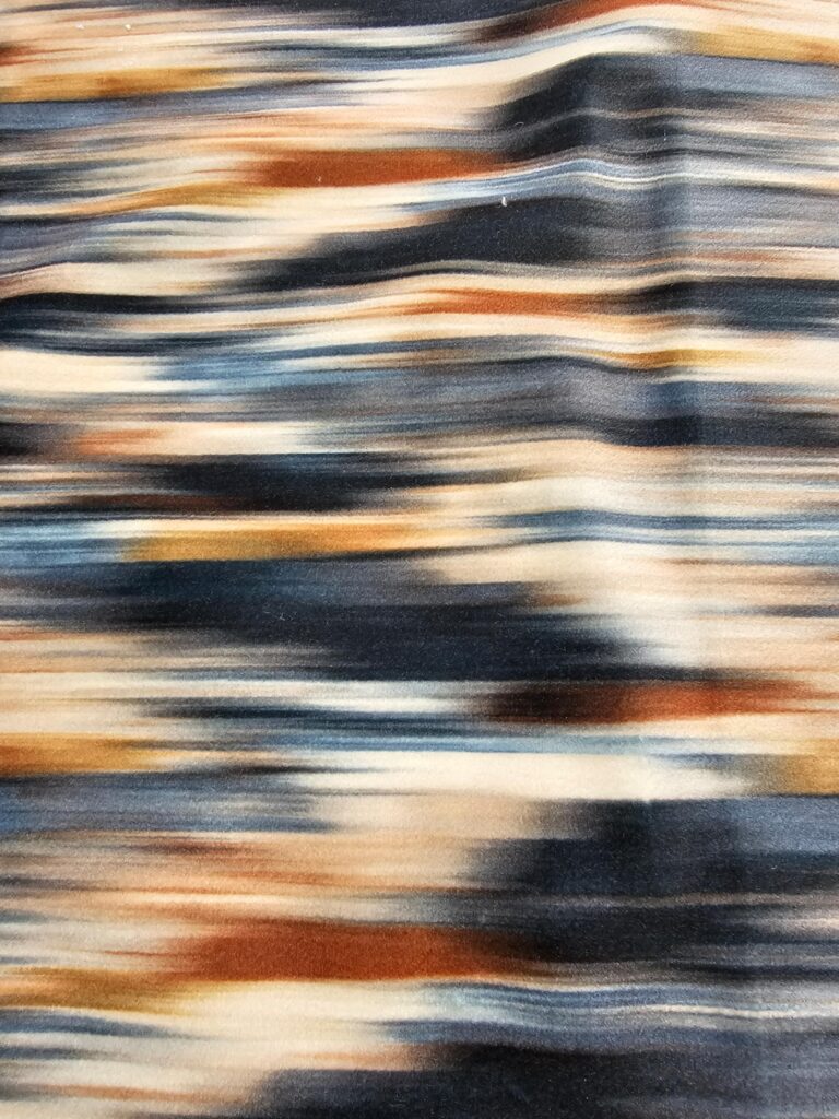 Close-up of velvet fabric in rust, navy, cream, and beige tones, used as the colour inspiration for custom pillows and decor in clairejefford’s Burlington bedroom makeover.